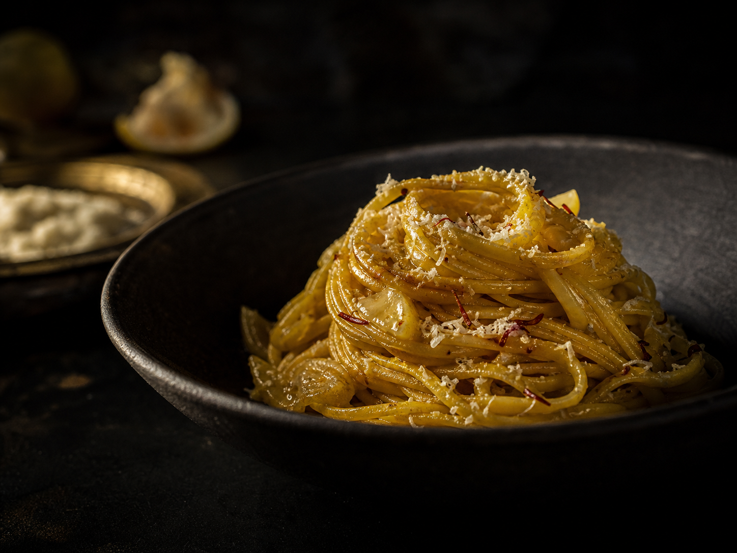 Saffron tagliolini with preserved lemon and aged cheese in a charcoal bowl